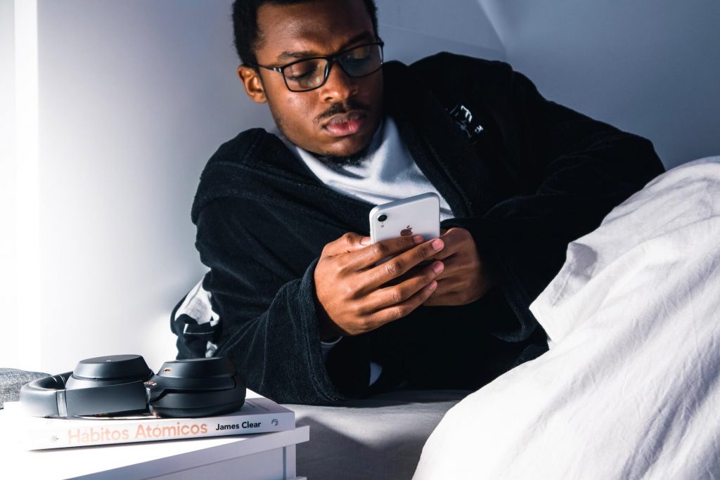 Un hombre usando su teléfono para monitorizar su sueño antes de acostarse, comprobando patrones de sueño y estadísticas