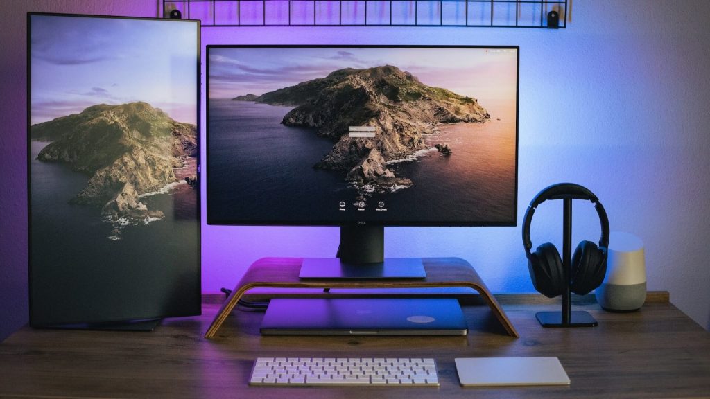 Un escritorio con dos monitores, un portátil y un teclado